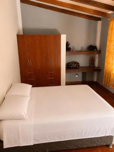 a bedroom with a white bed and a wooden cabinet at Depa Ángel in Moyobamba