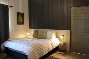 a bedroom with a bed with white sheets and green pillows at Favour House in Bethlehem