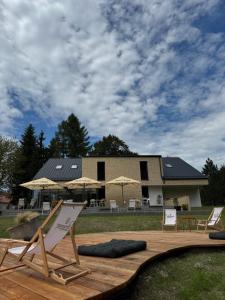 a deck with chairs and umbrellas in front of a house at Penzión ZAYDA in Výrava