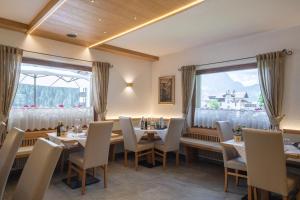 a dining room with tables and chairs and windows at HOTEL FONTANA in Sappada +39 photos
