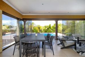 a dining room with a table and chairs and a pool at Alimama Spaces: Manson Mansion in Randjesfontein