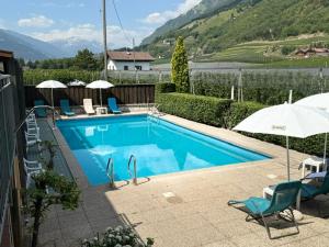 a swimming pool with chairs and umbrellas next to at Hotel Mondschein in Plaus