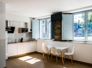 a kitchen with white cabinets and a table and chairs at A Calexa Sarria nº2 in Sarria