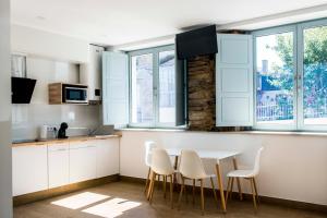 a kitchen with white cabinets and a table and chairs at A Calexa Sarria nº2 in Sarria +2 photos