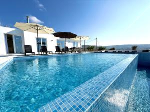 a swimming pool with chairs and umbrellas on a house at Seaview Panorama Villa in Drousha