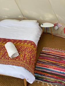 a room with two beds and a table and a rug at Au Pré Fleuri Eco Glamping in Le Lindois