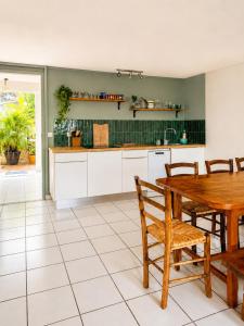 an open kitchen with a wooden table and chairs at Le Palmier Bleu, Spacious Duplex with Pool in Schœlcher