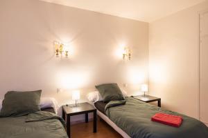 two beds in a room with two lamps on the wall at Gîte Le Scaphandre in Espalion