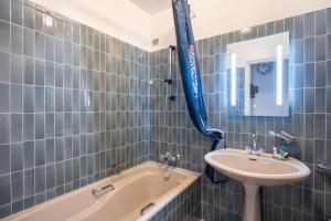a blue tiled bathroom with a sink and a bath tub at Gîte Le Lot in Espalion