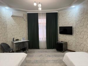 a hotel room with two beds and a table and a television at Royal Hotel Navoi in Navoi
