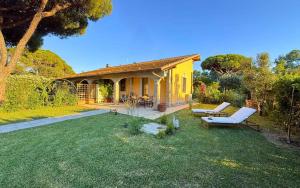 a small yellow house with a patio and a yard at Tenuta Fiumara in Marina di Grosseto