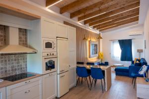 a kitchen and living room with white cabinets and blue chairs at Maria - Christina House in Soroni