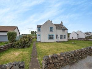 a house with a stone wall in front of a yard at Jura in Drummore