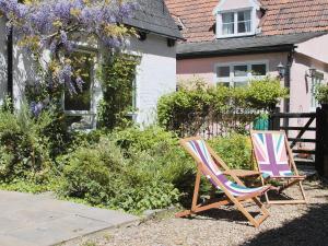 two lawn chairs sitting in a yard in front of a house at Crown Cottage in Hartest