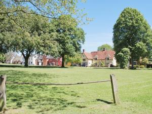 a fence in the middle of a field with houses at Crown Cottage in Hartest
