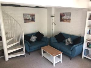 a living room with two blue couches and a staircase at Crown Cottage in Hartest +11 photos