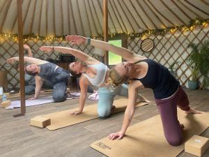 a group of people doing yoga in a tent at Yurtshire Eavestone Lake - Beech in Ripon +8 photos