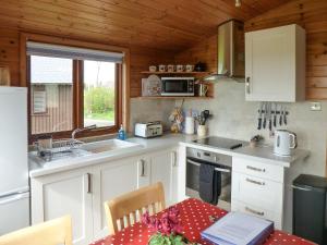 a kitchen with white cabinets and a table with a laptop at Wren Lodge - E5023 in Nawton