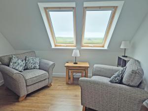 a living room with two chairs and a table at Husabost House in Carinish