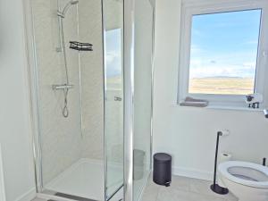 a bathroom with a shower with a toilet and a window at Husabost House in Carinish