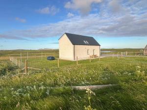 a small house in a field with a fence at Husabost House in Carinish