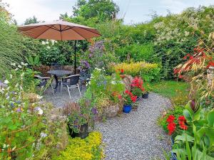 a garden with a table with an umbrella and flowers at Little Forda in Chillaton