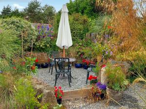 a table with an umbrella in a garden with flowers at Little Forda in Chillaton