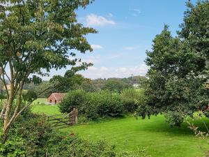 a green field with trees and a house in the distance at Little Forda in Chillaton +15 photos