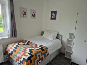 a bedroom with a bed with a colorful blanket on it at private room with shared bathroom 20 minutes walk to Durham centre in Gilesgate +4 photos