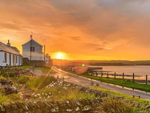 a sunset over a house and a church next to the water at Gigha in Drummore