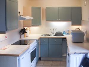 a kitchen with green cabinets and a sink at Gigha in Drummore
