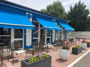 a patio with blue umbrellas and tables and chairs at Cit'Hôtel du Parc in Carrières-sous-Poissy