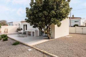 a white house with a tree and a table at Refúgio Do Loureiro in Sesimbra