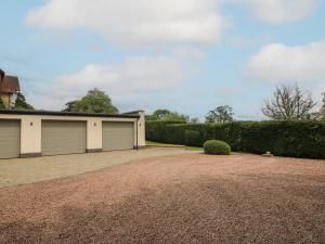 a house with two garage doors and a gravel driveway at The Butlers Quarters in Much Wenlock