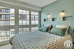 a bedroom with a bed and two windows at Ker helios in Dinard