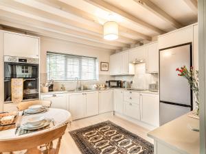 a kitchen with white cabinets and a table at Craven Bungalow in Allerston