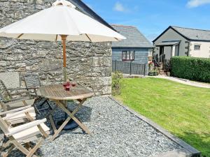 a table and chairs with an umbrella in a yard at Mum's Cottage - Uk52136 in Henwood