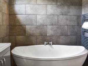a bathroom with a white tub and a tile wall at The Lune - Uk47035 in Kirkby Lonsdale