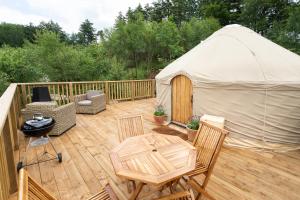 a gazebo with chairs and tables on a deck at Yurtshire Eavestone Lake - Beech in Ripon