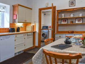 a kitchen with a table and chairs in a kitchen at Wren Cottage in Lydney