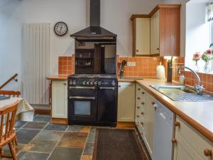 a kitchen with a black stove and a sink at Wren Cottage in Lydney +13 photos