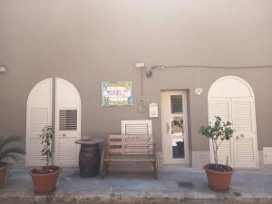 a building with two arched doors and a bench at B&B Sikelia in Terrasini