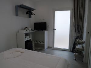 a white bedroom with a bed and a television at Mgd House in Santa Domenica