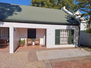 a white house with two chairs and a patio at Springbok Cottage in Graaff-Reinet
