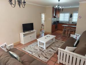 a living room with a couch and a tv at Springbok Cottage in Graaff-Reinet