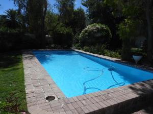 a swimming pool with blue water in a yard at Springbok Cottage in Graaff-Reinet