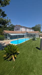 a large building with a swimming pool in a yard at Hotel & Restaurant Heliotel in Montferrier-sur-Lez