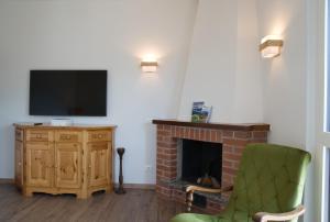 a living room with a fireplace and a green chair at Casa Rachele - mountain panorama in Cassina Valsassina