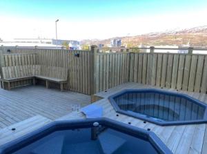 a patio with a hot tub and a bench on a deck at Tryggvabraut in Akureyri