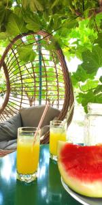 a table with two glasses of orange juice and a slice of watermelon at Garden house escape in Amarynthos